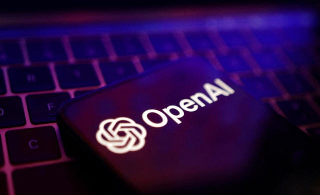 Un telefono celular con el logo de OpenAI, encima de un teclado de computadora